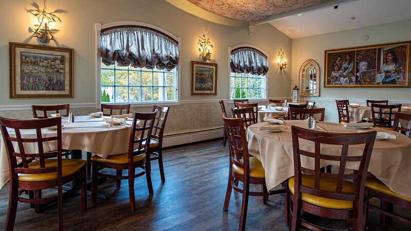 Rear dining room with four set tables and view of windows and painting